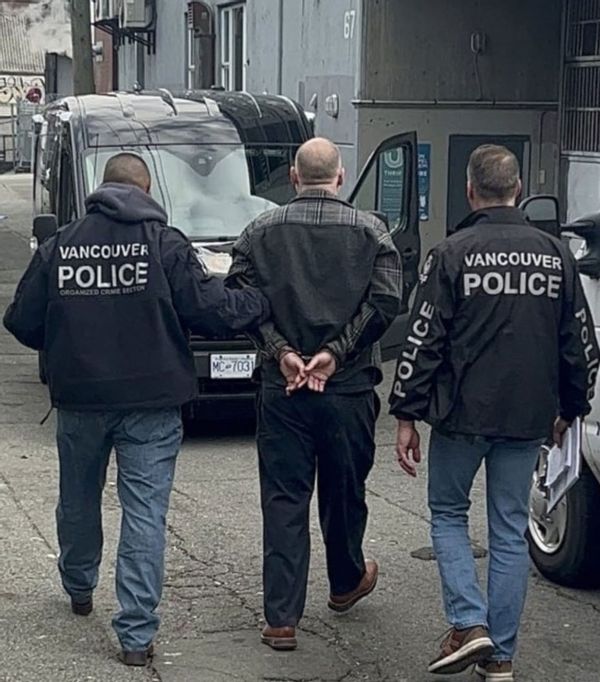 Фотография Ларсена, которого двое полицейских уводят к черному фургону.